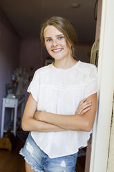 Portrait of pretty teenage girl leaning against doorway - CUF28644