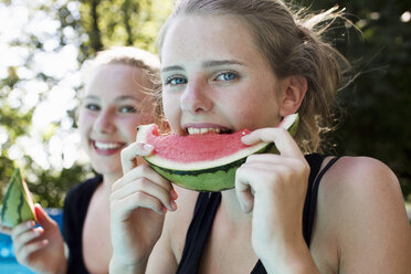 Zwei Teenager-Mädchen essen Wassermelonen-Scheiben im Garten - CUF28645