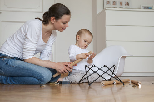 Mother and daughter assembling a chair at home - DIGF04584