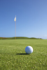 Close up of golf ball and golf flag on golf green - CUF28801