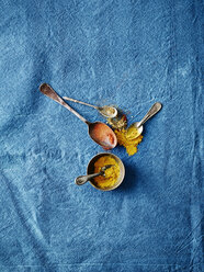 Overhead view of spoonfuls of turmeric and paprika spices on blue background - CUF29053