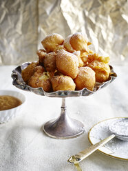 Bunuelos piled into silver serving dish dusted with icing sugar - CUF29073