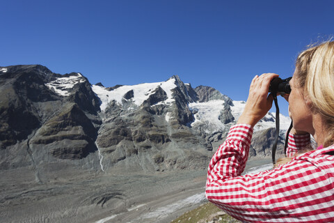 Österreich, Kärnten, Frau schaut durch ein Fernglas auf den Großglockner und den Pasterze-Gletscher, Blick von der Kaiser-Franz-Josefs-Höhe, Nationalpark Hohe Tauern, lizenzfreies Stockfoto