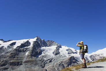 Österreich, Kärnten, Mann, Wanderer mit Fernglas beobachtet Großglockner, Nationalpark Hohe Tauern - GWF05535