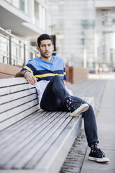 Portrait of fashionable young man sitting on bench - JATF01049