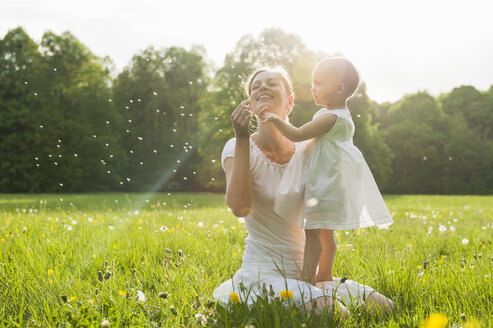 Mutter und Tochter mit Pusteblume auf der Wiese im Sommer - DIGF04598