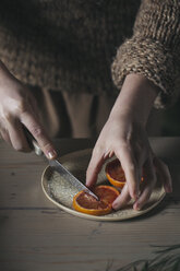 Woman's hands cutting slice of blood orange - ALBF00374