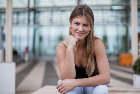 Porträt einer lächelnden jungen Frau, die im Freien sitzt - DIGF04603
