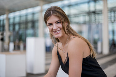 Portrait of smiling young woman sitting outdoors - DIGF04604