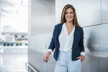 Portrait of smiling young businesswoman with luggage - DIGF04622