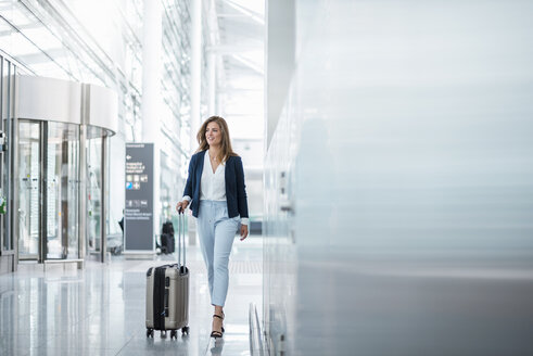 Junge Geschäftsfrau mit Gepäck auf dem Flughafen - DIGF04623