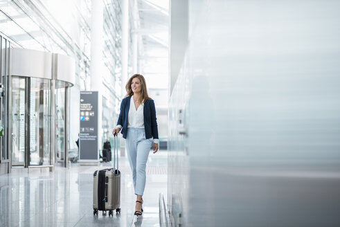 Young businesswoman walking with luggage at the airport - DIGF04623