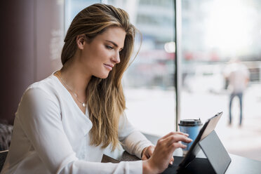 Young businesswoman in a cafe using tablet - DIGF04645