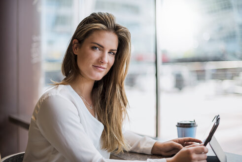 Porträt einer lächelnden jungen Geschäftsfrau in einem Café mit Tablet - DIGF04646