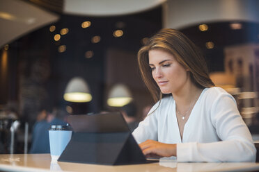 Young businesswoman in a cafe using tablet - DIGF04650