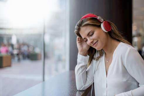 Lächelnde junge Frau, die mit Kopfhörern Musik hört - DIGF04651