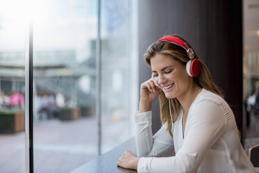 Happy young woman listening to music with headphones - DIGF04652