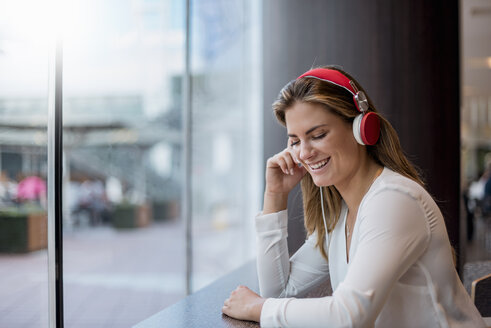 Glückliche junge Frau, die mit Kopfhörern Musik hört - DIGF04652