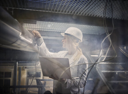 Female technician working on pipeworks, using laptop - CVF00764