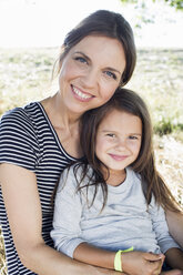 Portrait of mature woman and daughter sitting in park - CUF29087