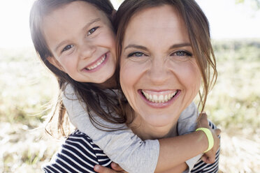 Portrait of mature woman giving daughter piggy back in park - CUF29088