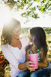 Ältere Frau und Tochter trinken beim Picknick im Park aus Pappbechern - CUF29090