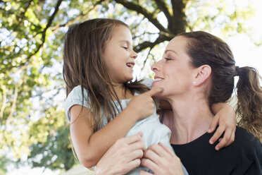 Mature woman carrying daughter in arms in park - CUF29101