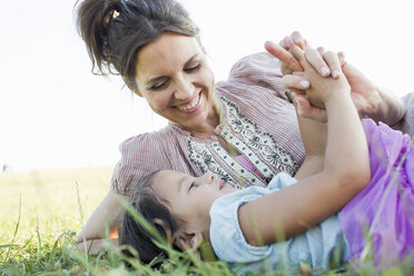 Mature woman and daughter reclining holding hands in park - CUF29109