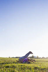 Mature woman and daughter rolling backwards in park - CUF29112