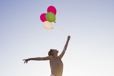 Niedriger Winkel Ansicht der reifen Frau hält bis Bündel von Ballons gegen blauen Himmel - CUF29115