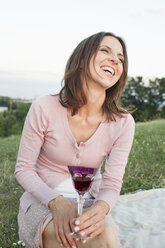 Ältere Frau lachend beim Trinken von Rotwein im Park - CUF29121