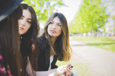 Three young female friends having conversation in park - CUF29135