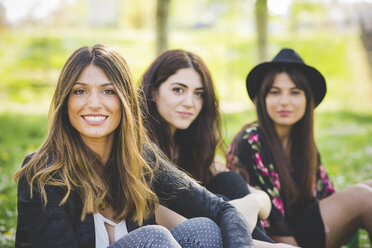 Portrait of three young female friends sitting in park - CUF29139