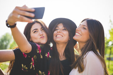 Three young female friends taking smartphone selfie in park - CUF29143