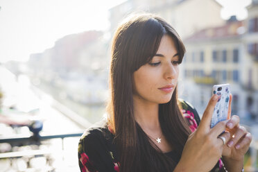 Junge Frau liest Smartphone-Texte auf einem Balkon am Wasser - CUF29147