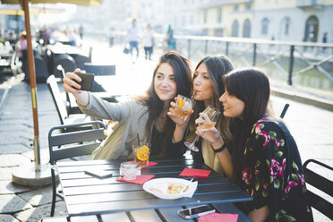 Drei junge Frauen posieren für ein Smartphone-Selfie in einem Hafencafé - CUF29149