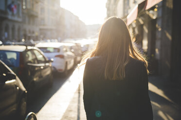 Rückansicht einer jungen Frau, die auf einer Stadtstraße spazieren geht - CUF29153