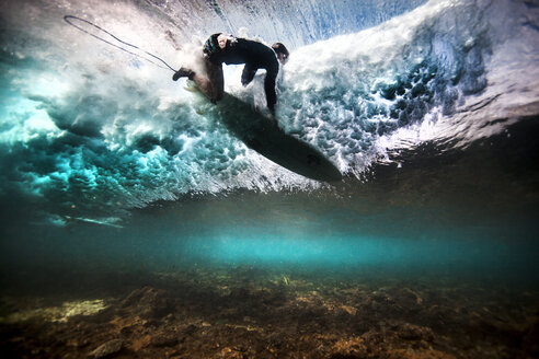 Unterwasseransicht eines Surfers, der nach einer Welle auf einem flachen Riff in Bali, Indonesien, durch das Wasser fällt - CUF29160