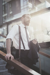 Stylish businessman carrying jacket moving down city stairway - CUF29170