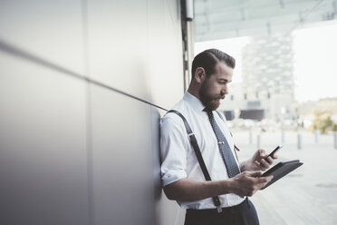 Eleganter Geschäftsmann nutzt Smartphone und digitales Tablet außerhalb des Büros - CUF29177