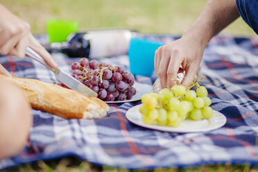 Beschnittene Ansicht von Paaren Hände greifen für Trauben auf Picknickdecke - CUF29182