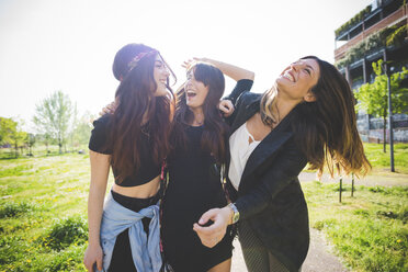 Drei junge Freundinnen lachen zusammen im Park - CUF29196
