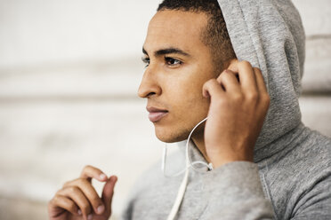 Male runner wearing grey hoody listening to earphone music - CUF29214