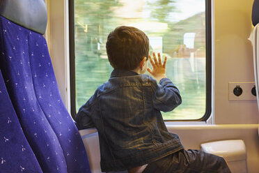 Rear view of boy with his hand against train carriage window - CUF29267