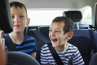 Zwei glückliche junge Brüder auf dem Rücksitz eines Autos - CUF29268