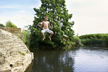 Teenage boy jumping mid air into lake - CUF29285