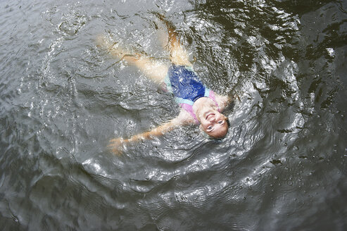 Overhead view of girl swimming in rural lake - CUF29287