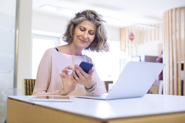 Portrait of senior female designer texting on smartphone in office - CUF29291