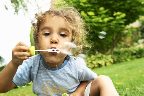 Close up portrait of cute girl blowing bubbles in garden - CUF29342