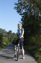 Mature cyclist with bicycle on rural road - CUF29355